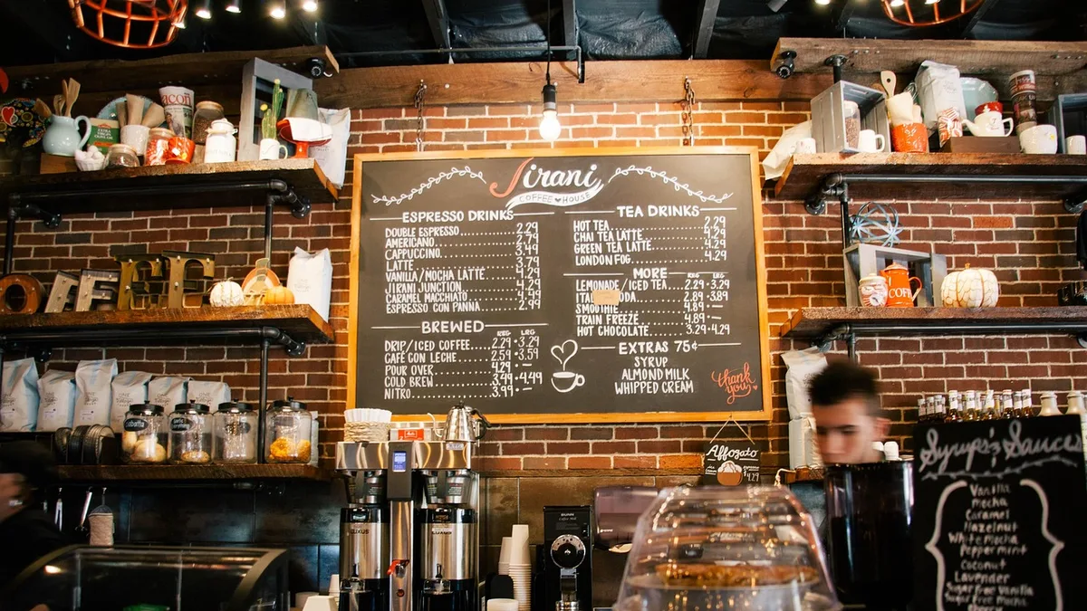 Barista taking a customer order at the register of a busy coffee shop counter